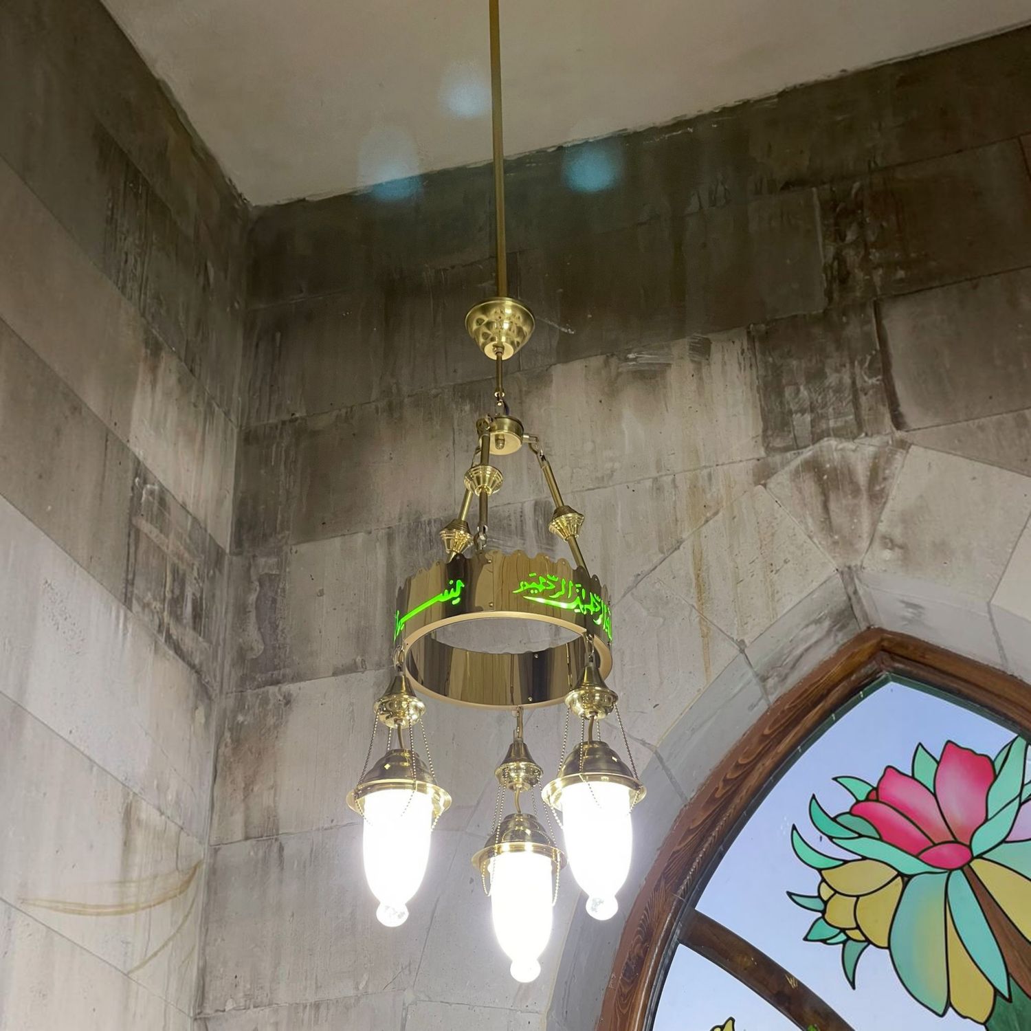 Tek halkalı 30 cm yeşil besmeleli ledli cami avizesi cami içinde, taş duvarın yanında yanarken