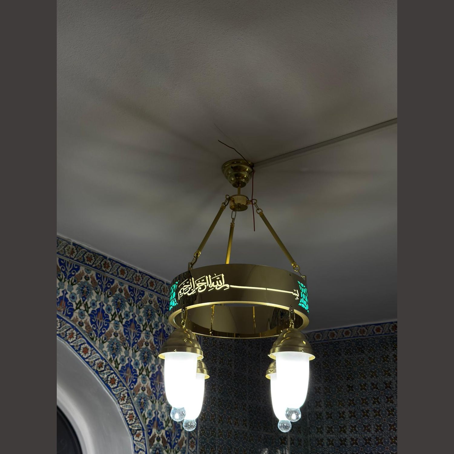 Tek halkalı 40 cm turkuaz tevhidli ledli cami avizesi cami içinde, çinili duvarın yanında yanarken
