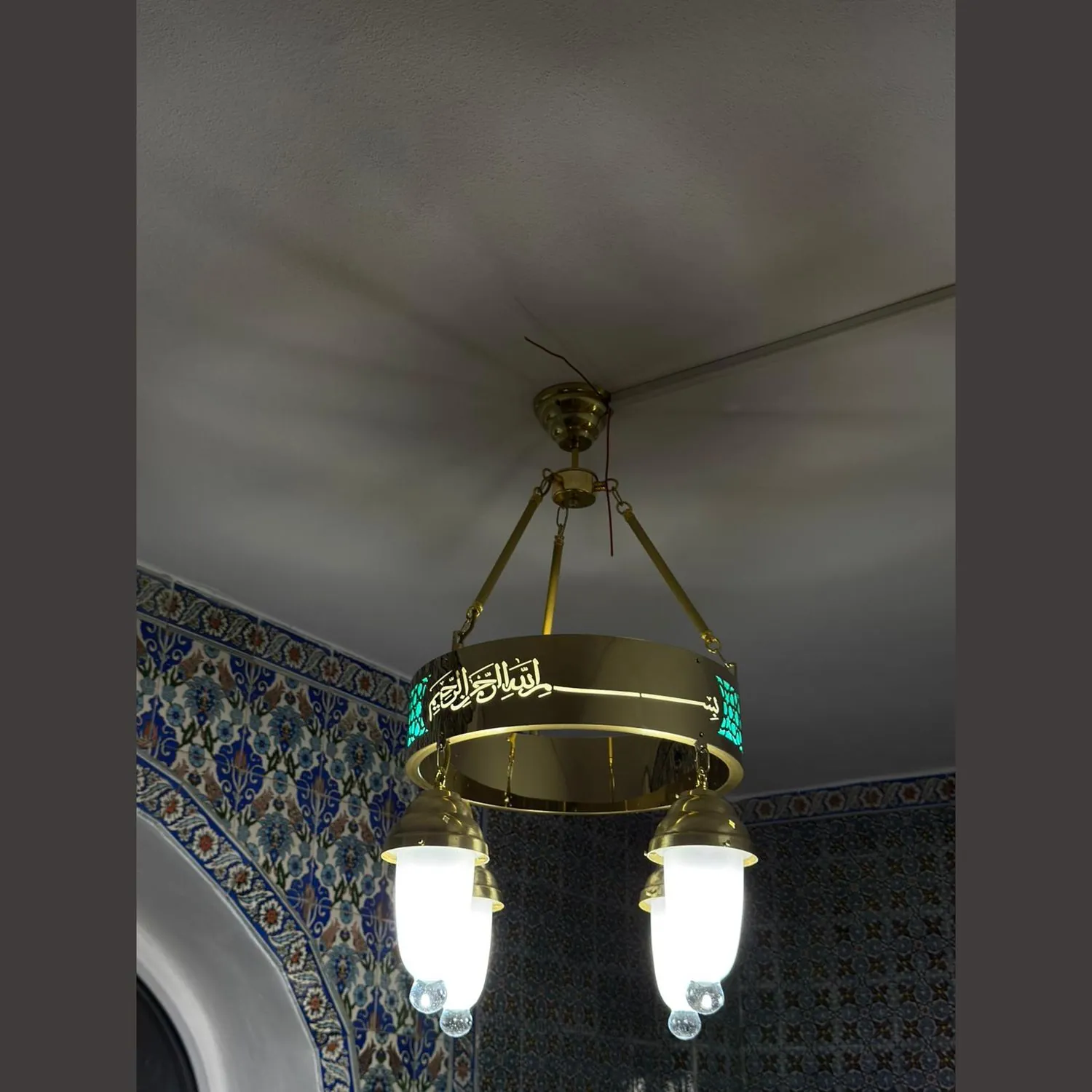 Tek halkalı 40 cm turkuaz tevhidli ledli cami avizesi cami içinde, çinili duvarın yanında yanarken