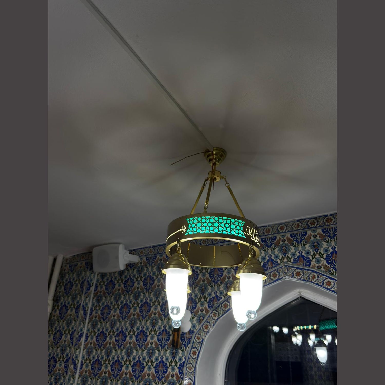 Tek halkalı 40 cm turkuaz tevhidli ledli cami avizesi çinili mekânda, tavan bağlantısı görünür hâlde