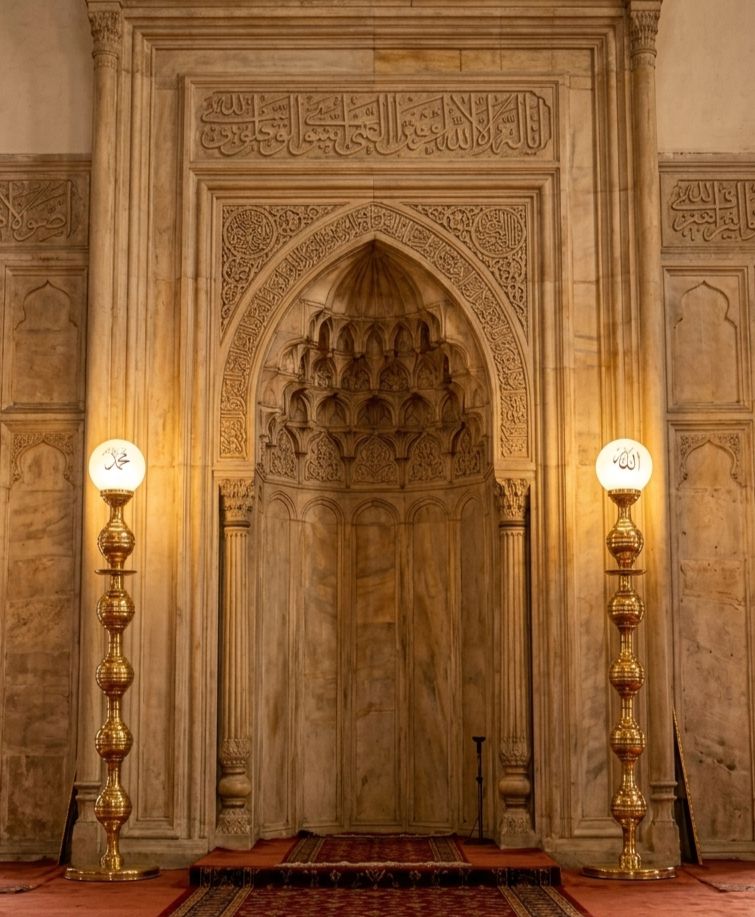 Cami mihrabının iki yanında Osmanlı şamdan takımı; ışıklı küre başlıkta Allah ve Muhammed yazısı