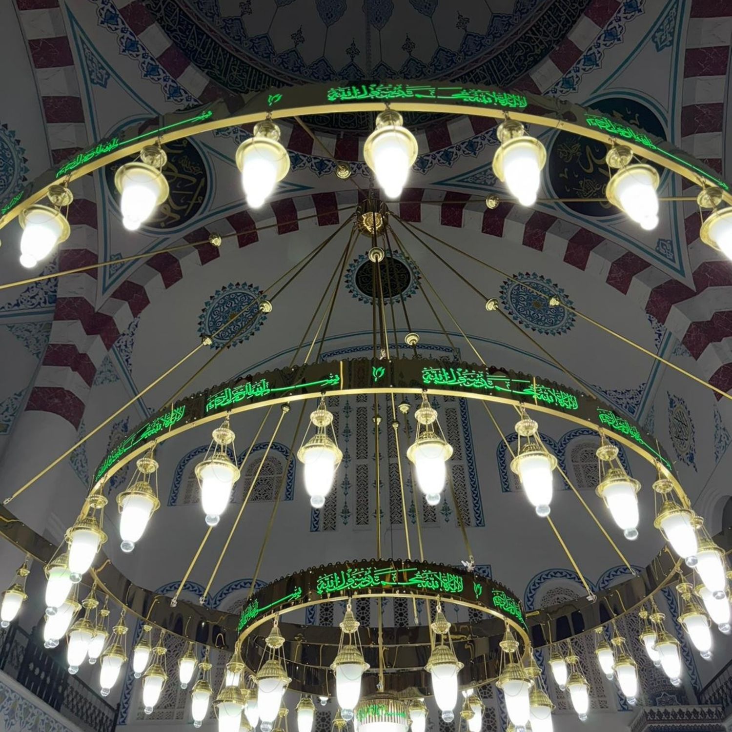 Üç kademeli yeşil tevhidli ledli cami avizesi mihrap önünde, kubbe altında yanarken
